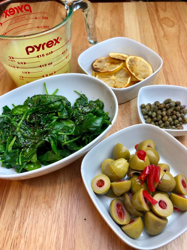 ingredients for recipe; broth, olives, capers, spinach, roasted lemons