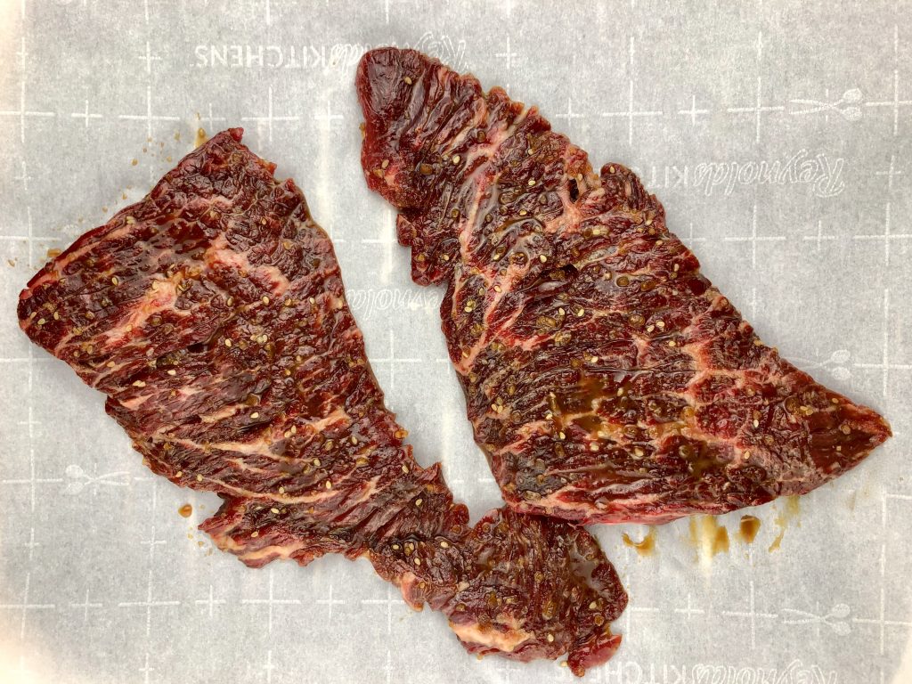Marinated skirt steak on parchment paper, ready to get broiled