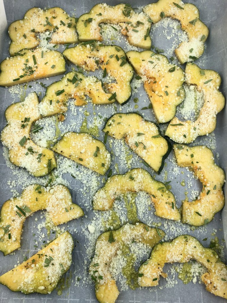 acorn squash slices sprinkled with olive oil, fresh herbs, garlic spice rub and parmesan