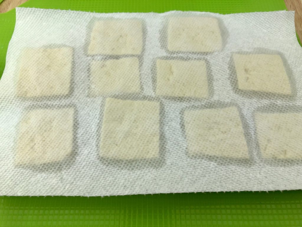 And place paper towel on top of tofu squares, press to remove liquid