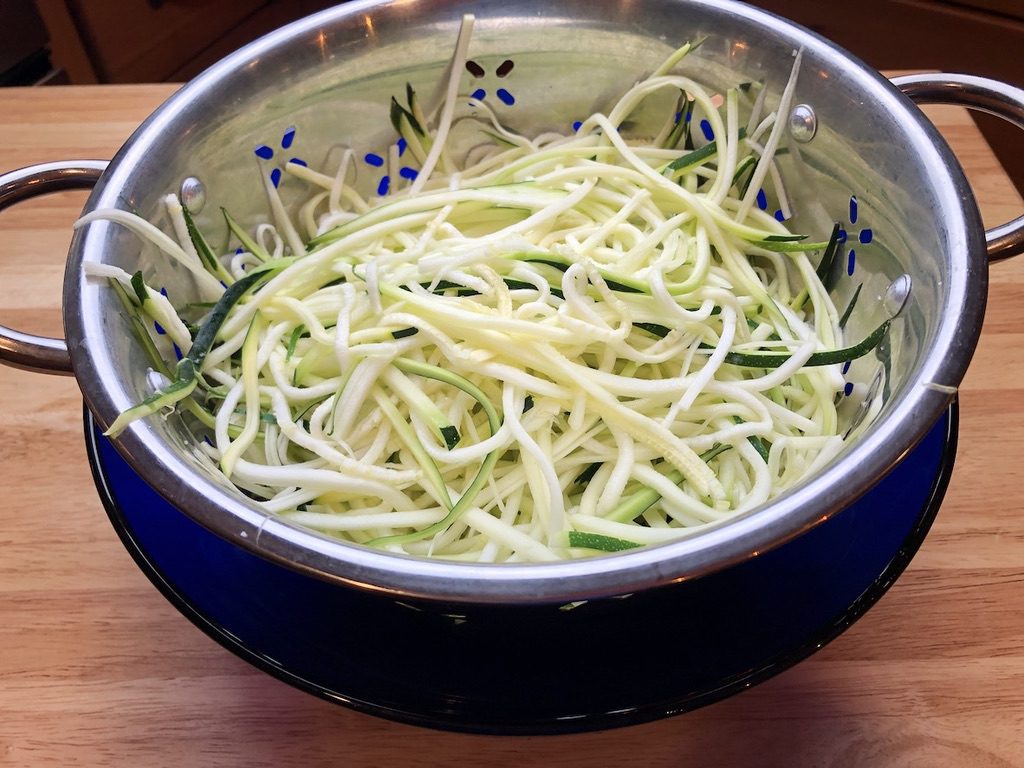 salted zucchini strands, in a strainer