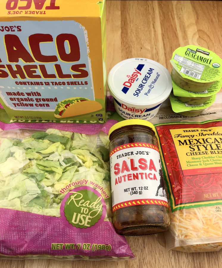 taco fixings (lettuce, sour cream, avocado, salsa, guacamole and shredded cheese) and shells