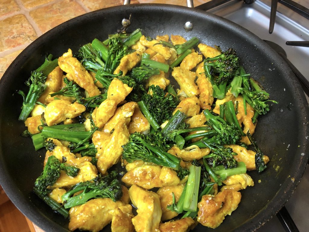 cooked turmeric chicken pieces with broccolini mixed in