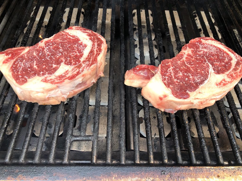 placing the rib eyes on the grill