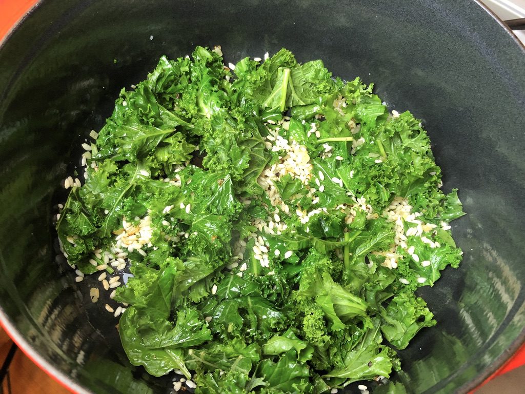 torn kale added to risotto