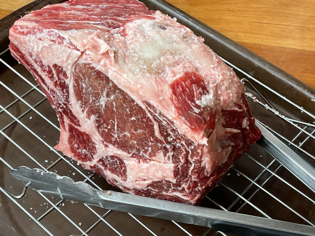 bone-in rib roast resting on rack in a roasting pan for 2 hours at room temp