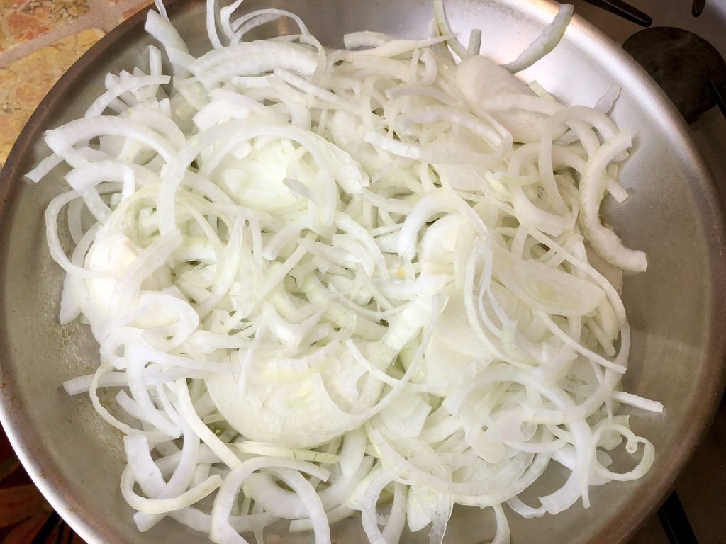 thinly sliced onions in the pan