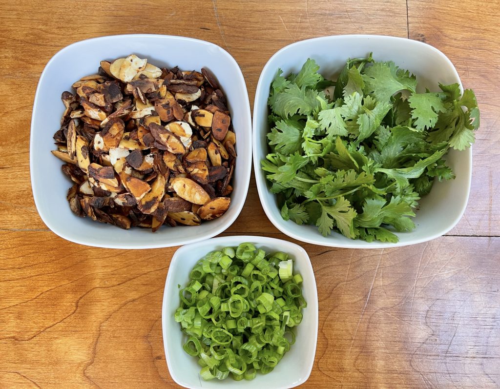 Garnish with cilantro leaves, scallions, and soy-glazed almonds