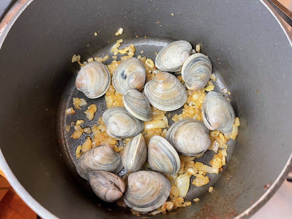add clams to the pot with the remaining onions and garlic, place a lid on the pan. 