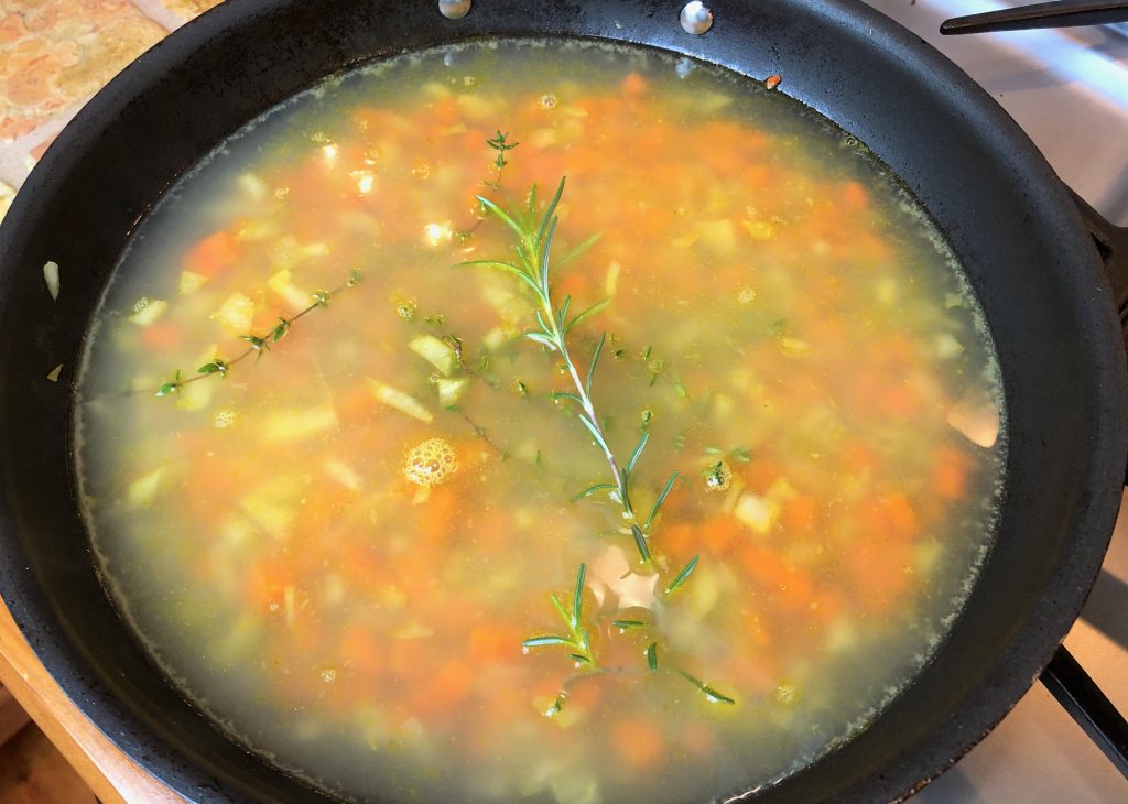 adding the broth/stock and herbs to the vegetables