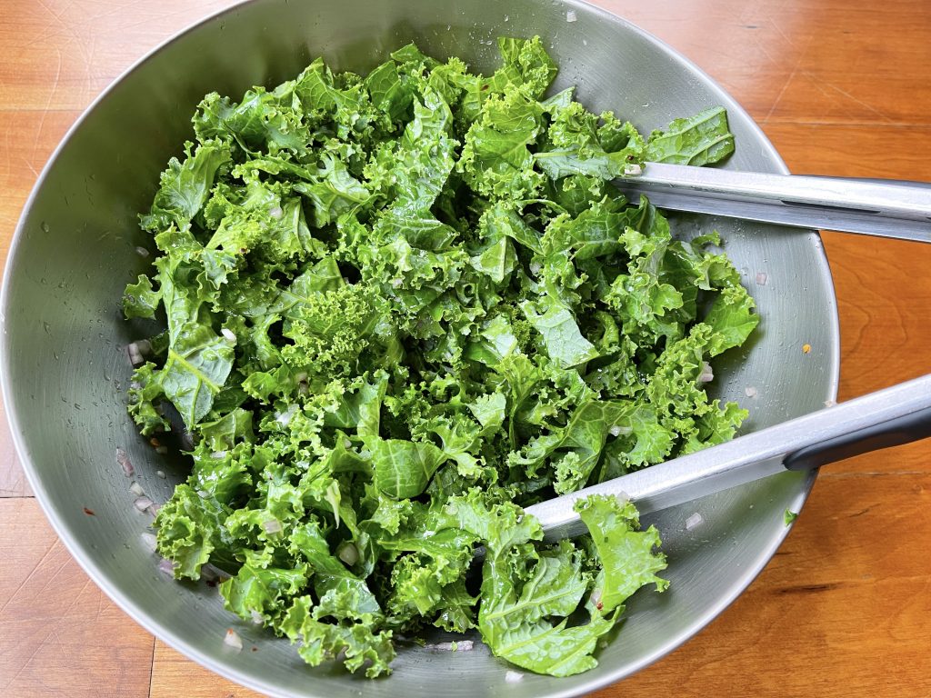 Adding kale on top of dressing base. mix with tongs and let rest at least 20 mins or overnight