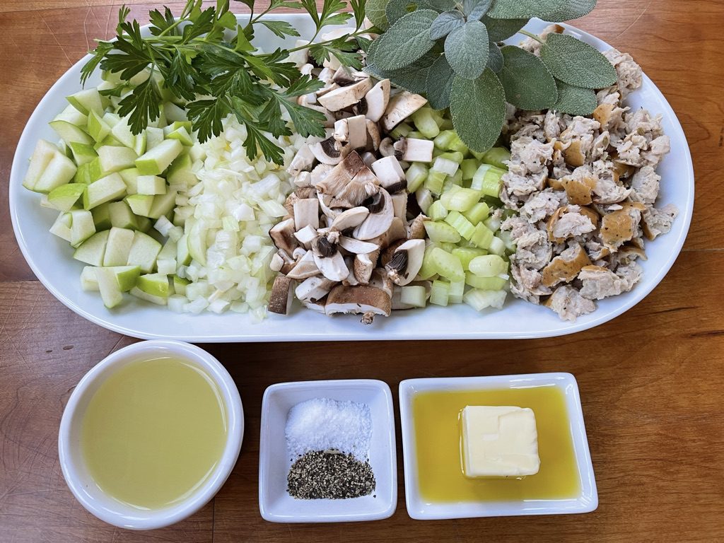 stuffing ingredients - diced apples, mushrooms, onion and celery, chicken broth, fresh herbs (parsley and sage), olive oil, butter, and salt and pepper
