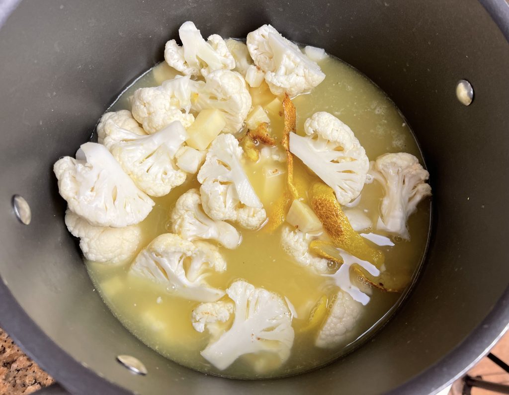 Add cauliflower, potatoes, garlic, and broth to the pot