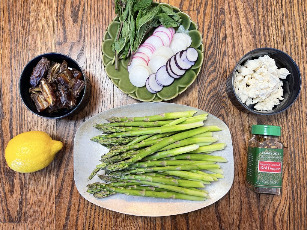 Ingredients for the dish - asparagus, dates, goat cheese, radishes, lemon, mint, and red pepper flakes.