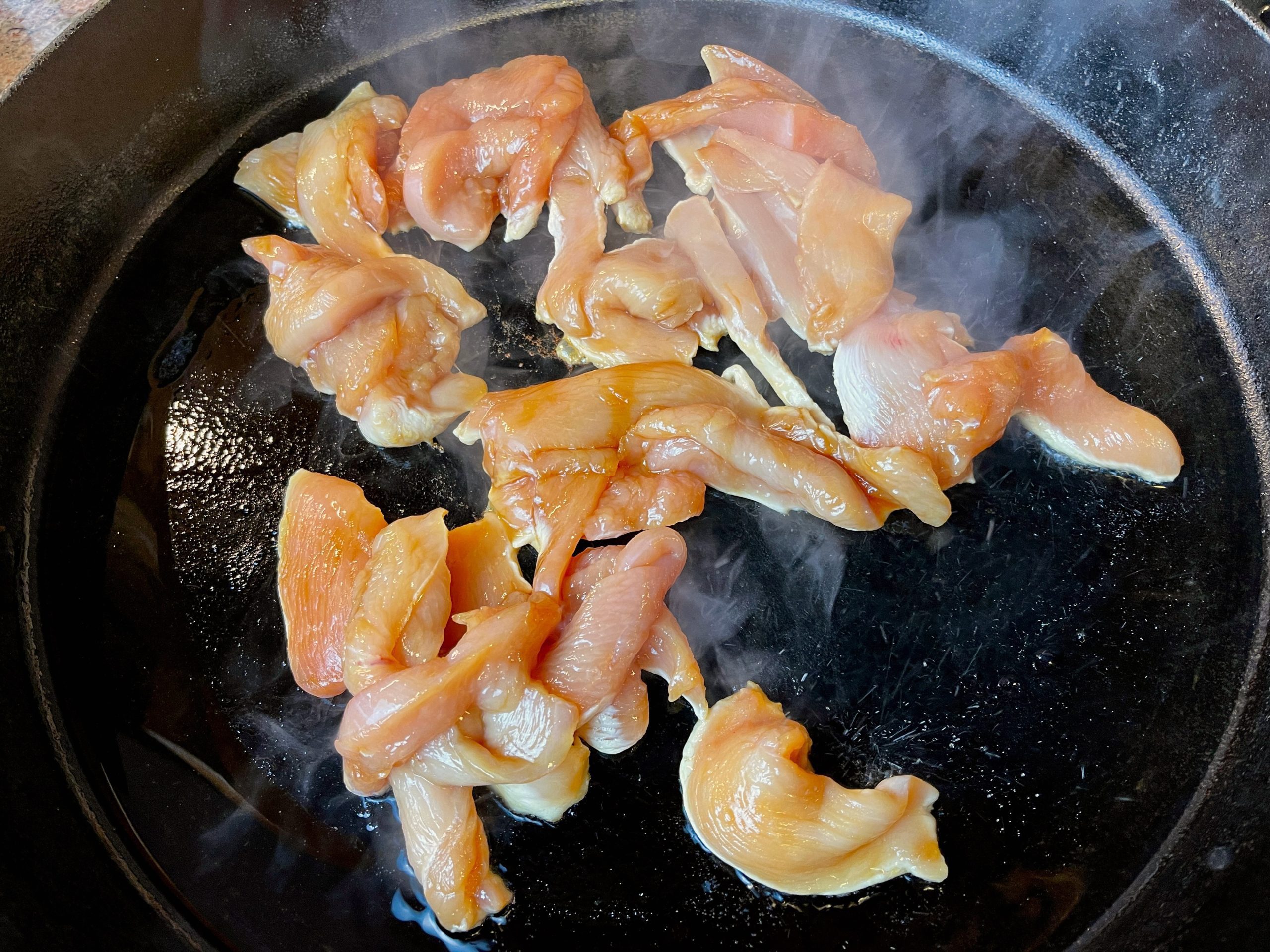 Heat oil in a large pan over high heat.  Add chicken to the pan once the oil is almost smoking. Cook undisturbed for 1 minute to achieve a nice sear (browning.)
