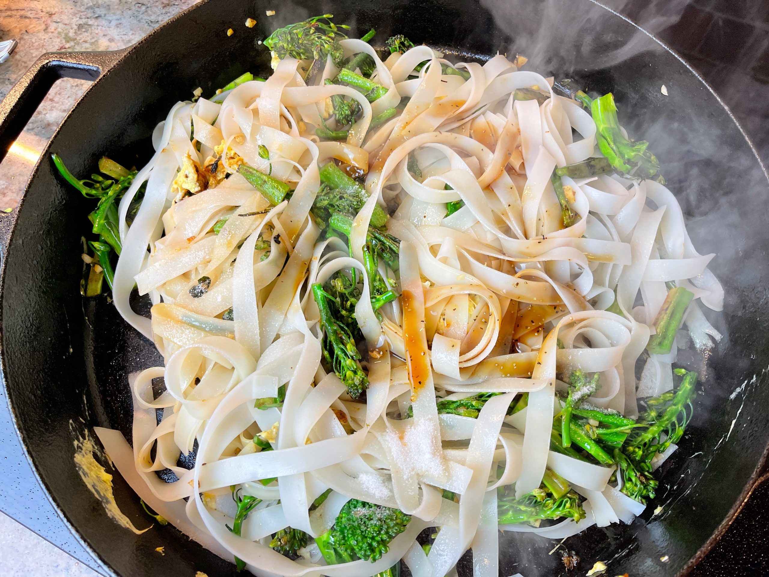 Once noodles are mixed in and heated through, add the sugar and sauce. Mix together with tongs.