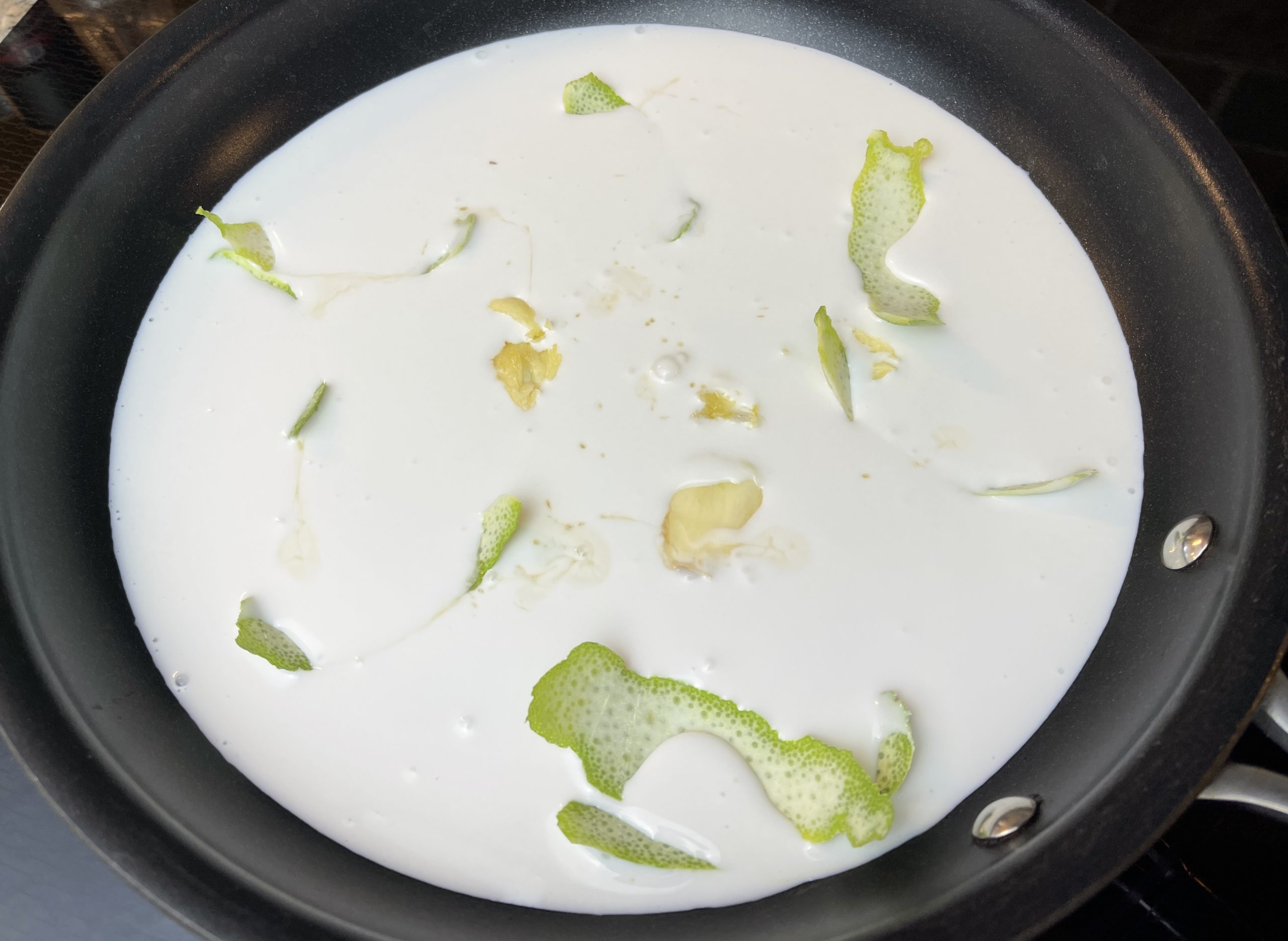 Heat coconut milk with lime zest, garlic, and fish sauce