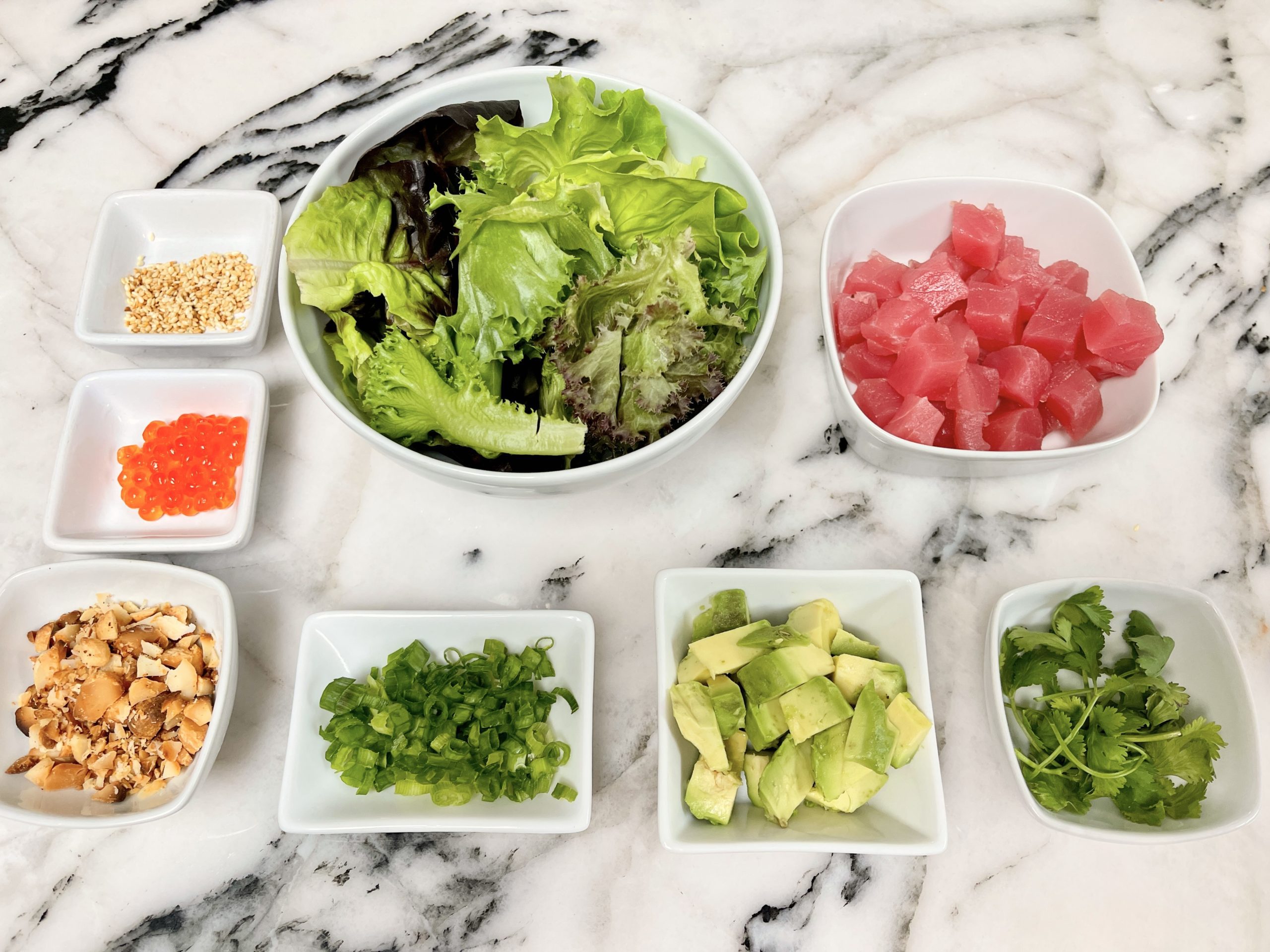organize all of the Poke ingredients - lettuce, diced tuna, diced avocado, scallions, cilantro, toasted macadamia nuts, toasted sesame seeds, and roe (optional)