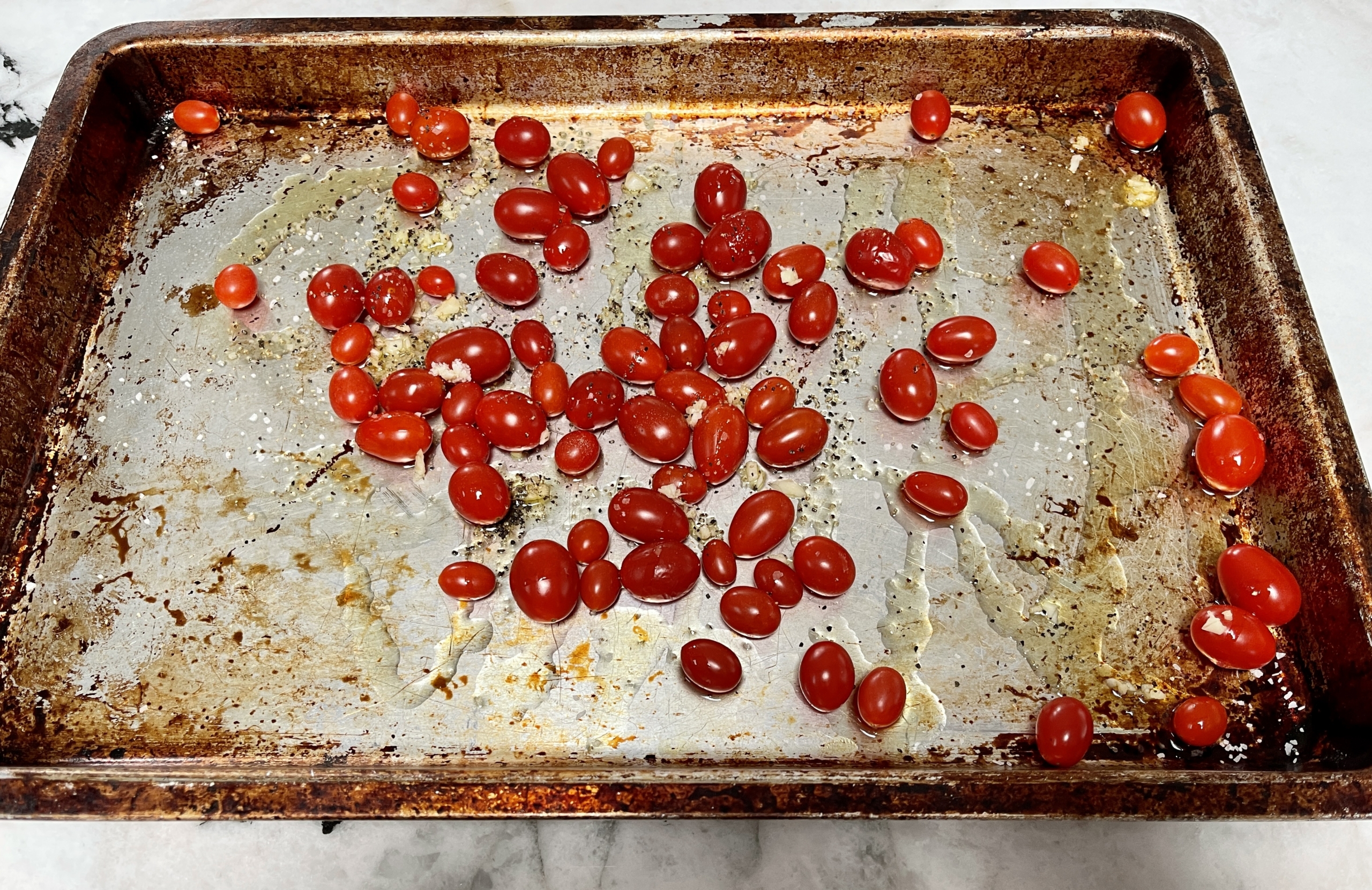 Place cherry or grape tomatoes on a sheet pan and drizzle with olive oil, salt, pepper, and garlic.