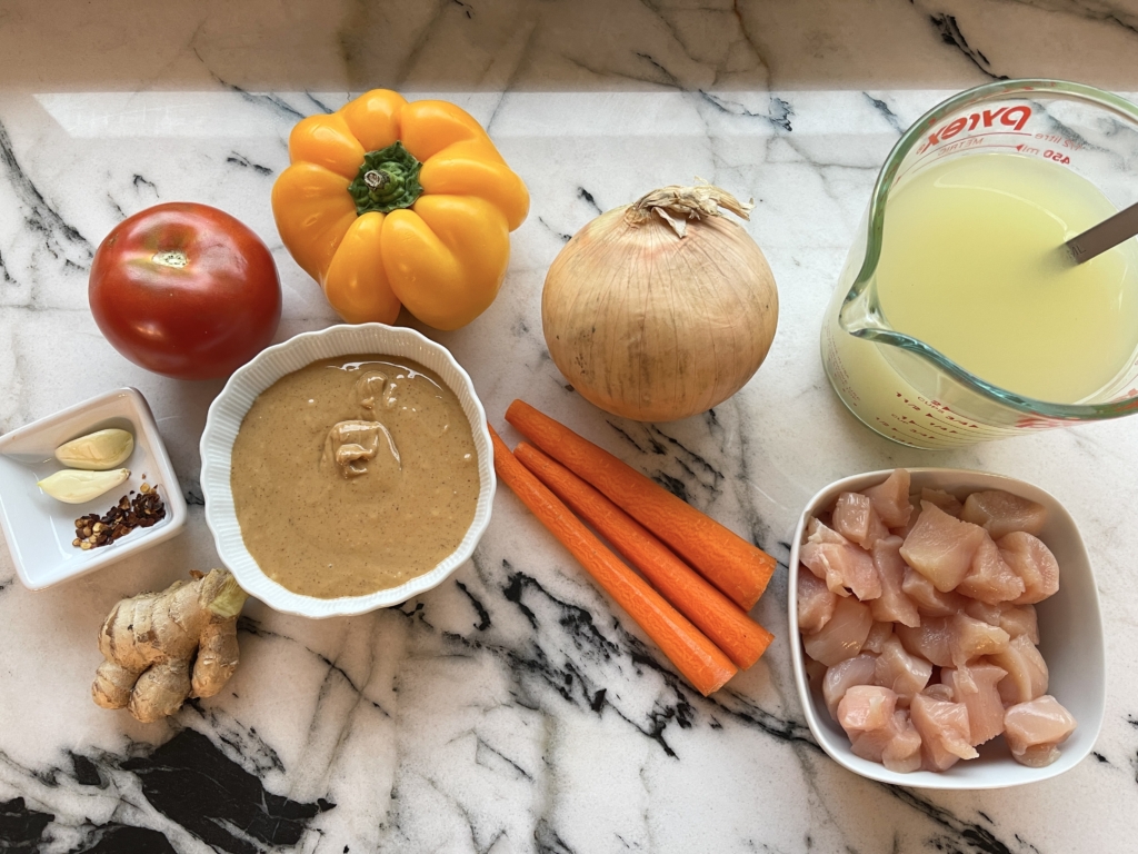 soup ingredients - onion, tomato, ginger, garlic, peanut butter, broth, chicken, bell pepper, carrot, hot pepper flakes, and salt.