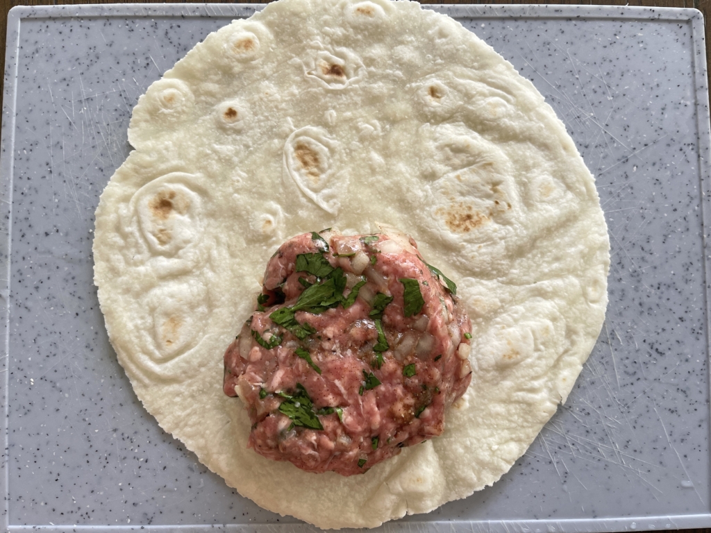 place lamb patty close to the outer edge of the tortilla.