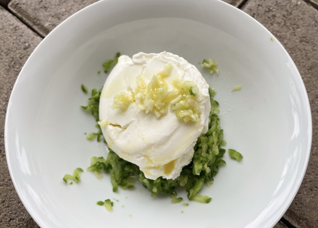 place grated cucumbers, greek yogurt, olive oil, garlic, distilled white vinegar, squeeze of lemon (optional), fresh mint and/or dill (optional) in a medium sized bowl.