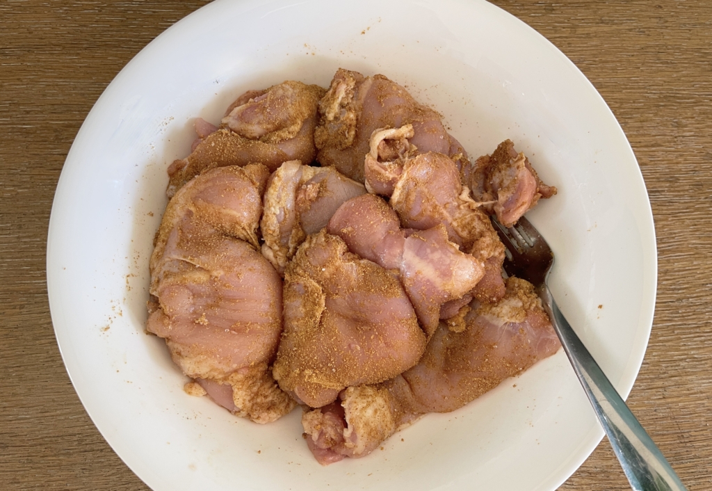 Using tongs, a fork, or your hands, mix chicken with spices until chicken pieces are thoroughly coated
