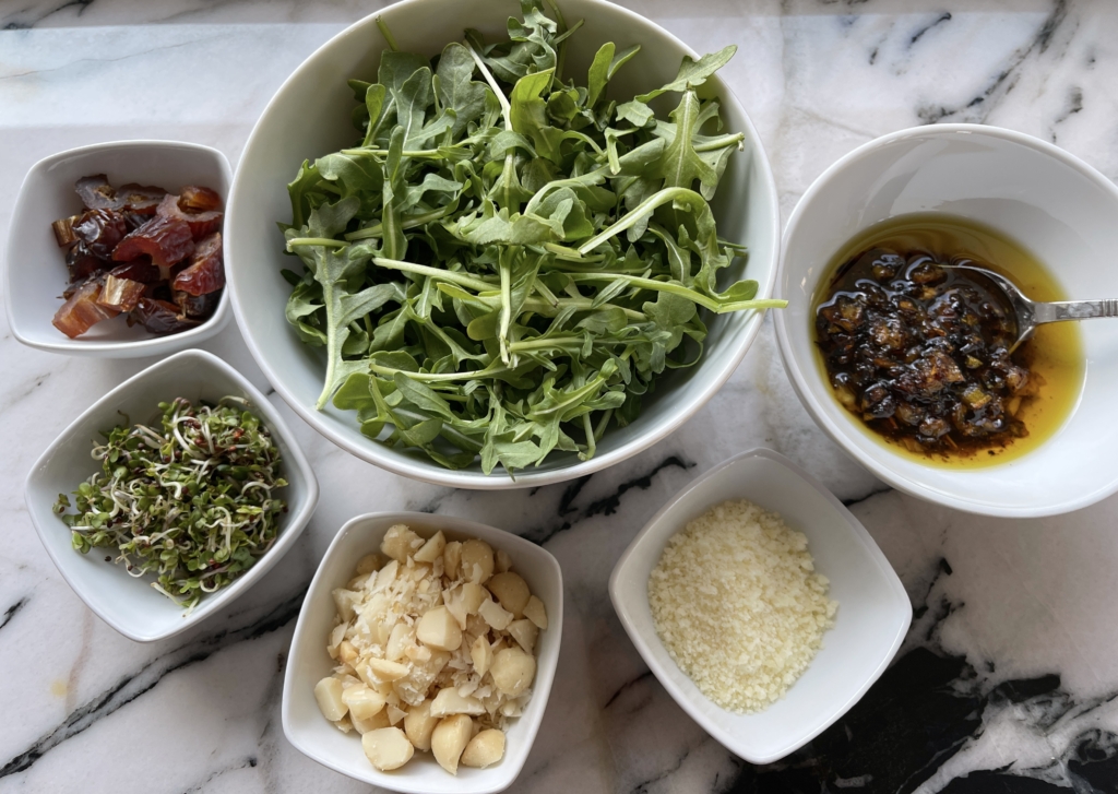 sample salad ingredients - arugula, chopped macadamia nuts, chopped dates, sprouts, and parmesan cheese with Caramelized Lemony Dressing