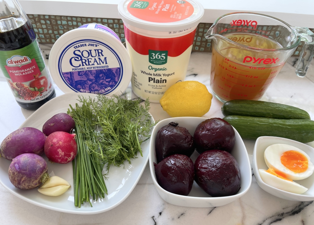 Soup ingredients: roasted beets, cucumbers, radishes, broth, garlic, lemon juice, sour cream, plain yogurt, chives, dill, jammy eggs, and pomegranate molasses.