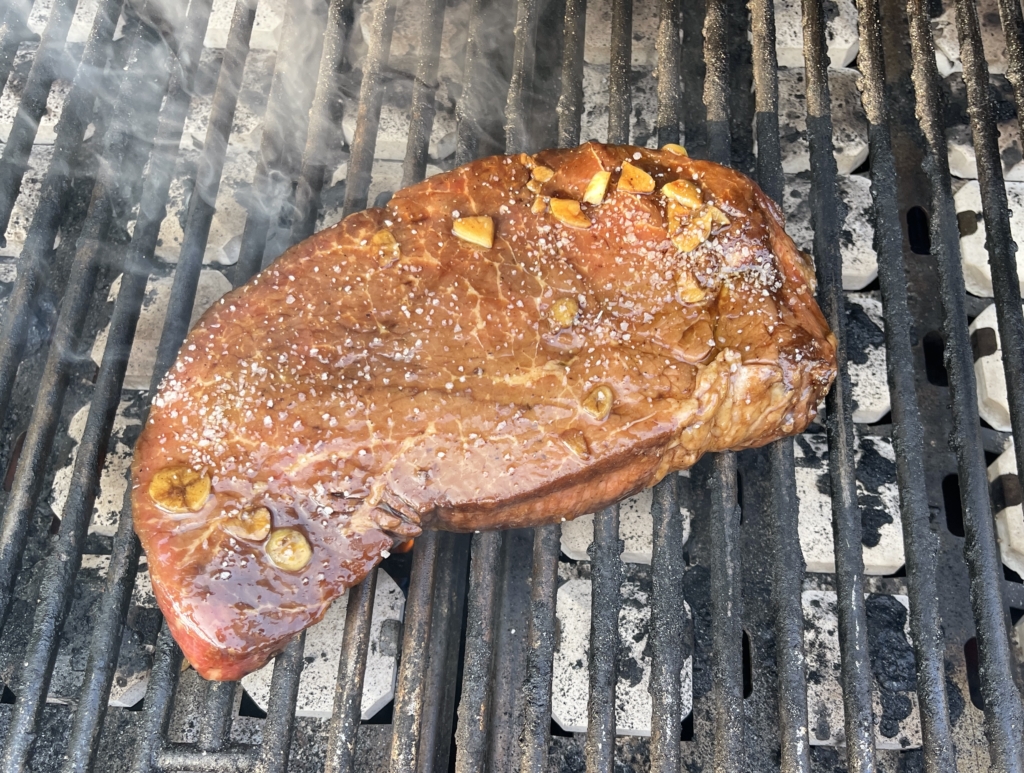 Using tongs, take the london broil out of the marinade and place meat on a pre-heated grill on medium-high heat for 8 mins.