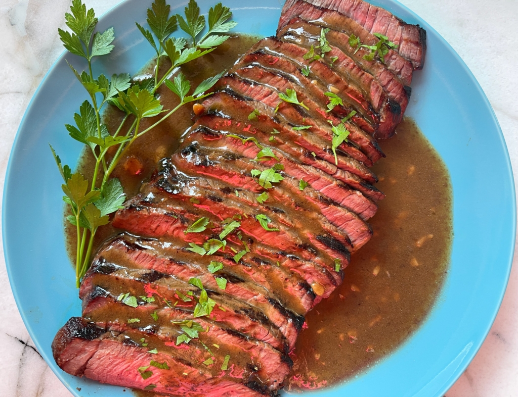 Let london broil rest for 10 mins and then thinly slice across the grain. Place meat on a platter and marinade/sauce on top. Garnish with some chopped herbs (parsley, chives, scallions, etc)