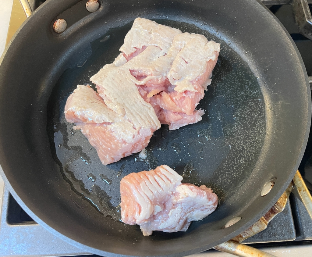 Place ground chicken in a large non-stick pan that's been heated over medium-high heat with neutral and sesame oil. Season chicken with kosher salt and pepper.