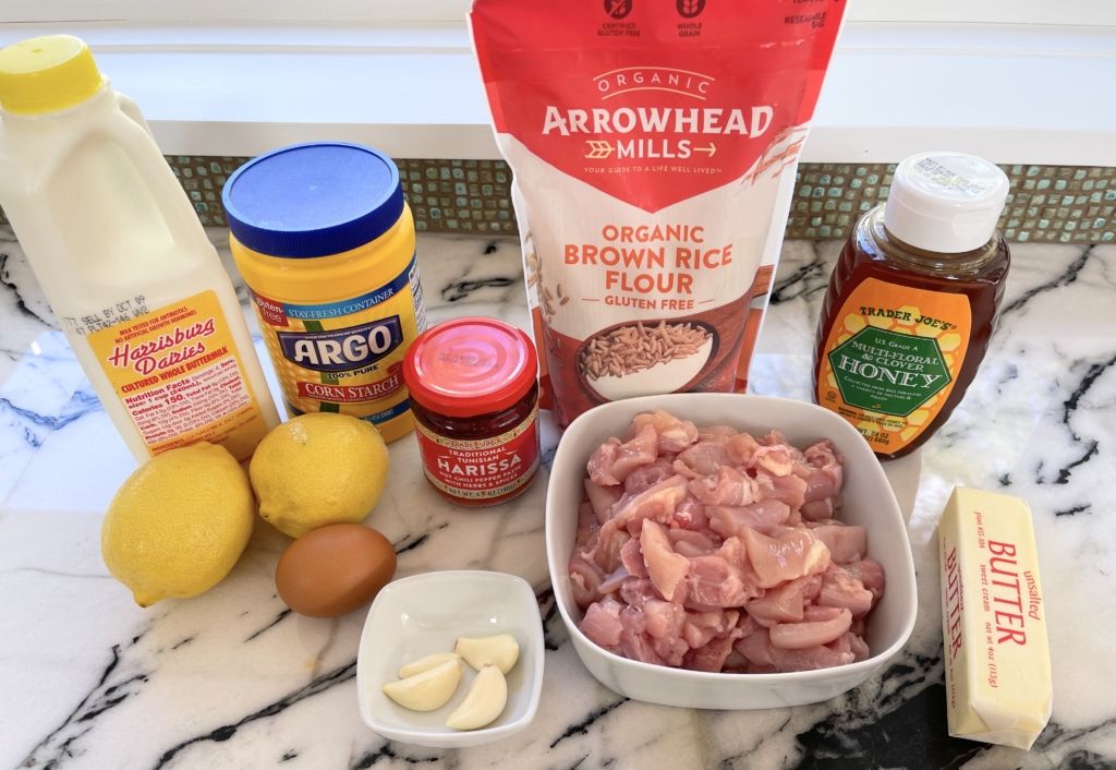 Organize the ingredients - cut-up chicken thighs, brown (or white) rice flour, cornstarch, buttermilk, egg, lemon zest and juice, garlic, harissa paste, honey, and butter.