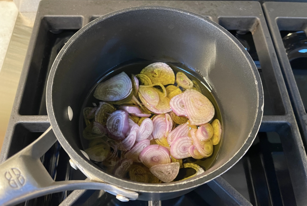 Add sliced shallots to olive oil in a small saucepan over medium heat.