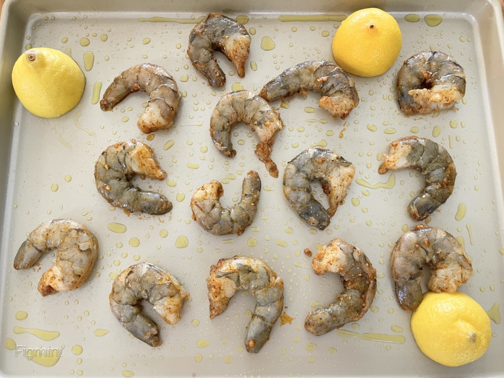 Place one tablespoon of olive oil on a baking sheet and coat pan using a silicone brush, if needed. Place shrimp and three lemon halves (cut-side down) on the baking sheet. 