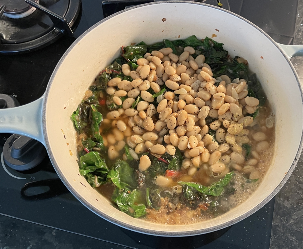 Next, add the beans and broth and stir to combine. Bring broth to a boil, then turn heat to low and simmer, mashing some of the beans with a large spoon, until the liquid has reduced and thickened, 6 to 8 minutes.