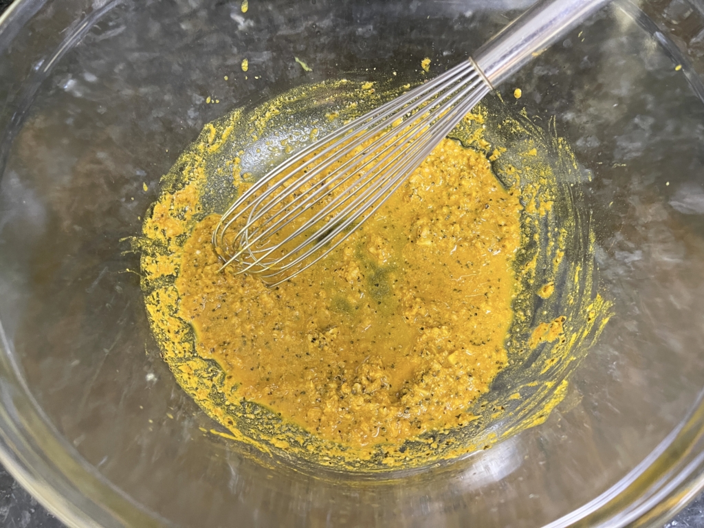 While the oven is heating, marinate the chicken. In a large bowl, combine 2 tablespoons olive oil, lemon juice, garlic, ginger, 1½ teaspoons of the salt, turmeric, coriander and pepper, and mix well. 