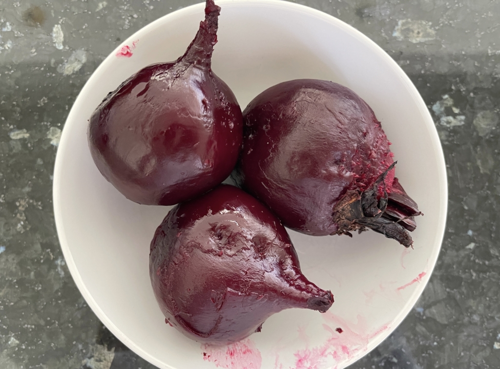 let beets slightly cool and then using a paper towel or disposable gloves, rub the skin off the beets. The skin should easily come off. If this isn't the case, re-wrap the beets in the foil and cook the beets for an additional 10 mins.