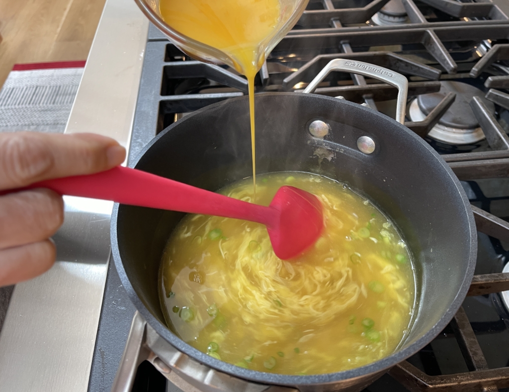 Once soup is thickened slightly, it’s time to add the egg to the broth. Reduce the heat to medium-low. Then, very slowly stir the broth in a circular motion, and simultaneously slowly drizzle the beaten eggs in a thin stream into the pot.