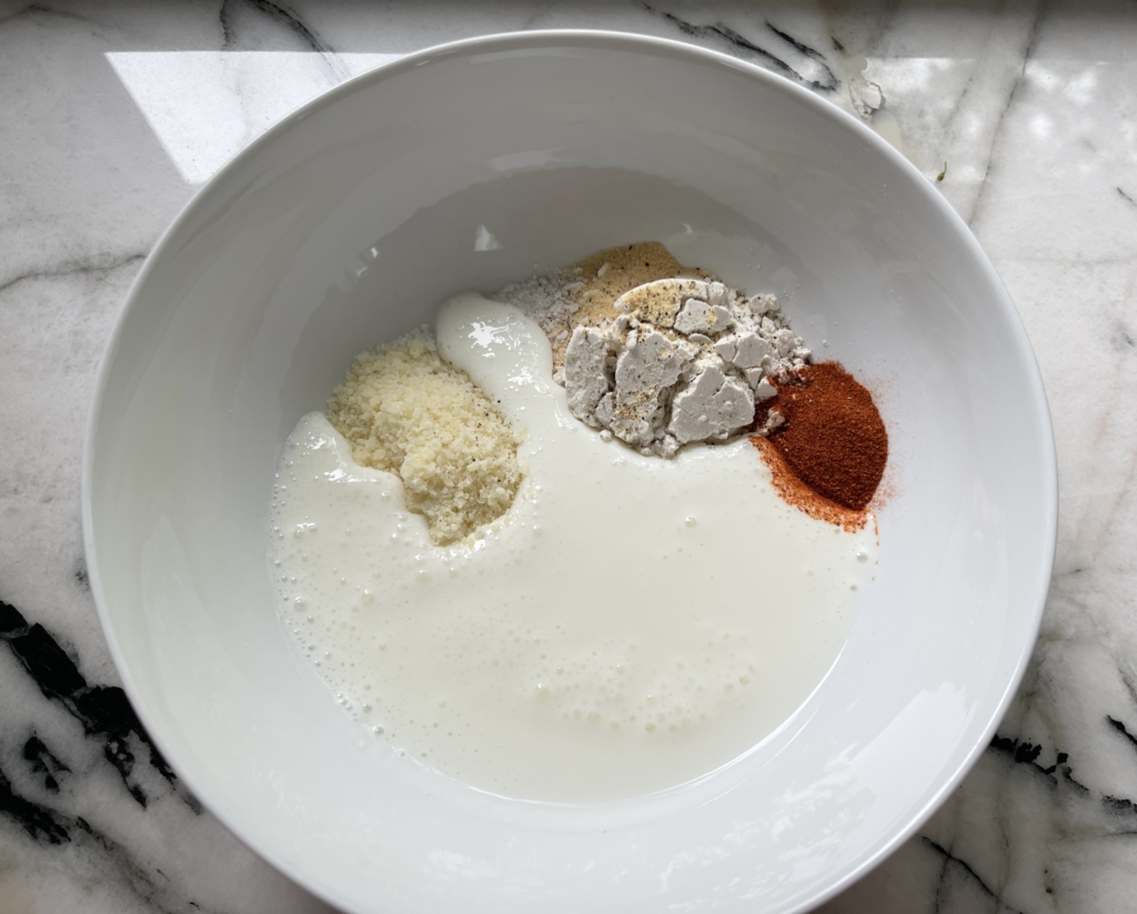 Place gluten free flour, milk, garlic powder, paprika, parmesan, kosher salt and freshly ground pepper in a medium-large bowl.