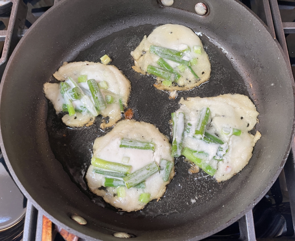 Heat a large non-stick pan with oil over medium-high heat and once heated, spoon in approximately 2 tablespoons of batter with scallion and leek pieces into the pan, trying not to have the pancakes touch each other. Reduce to medium heat and fry until the bottoms are crispy golden brown and the onions are slightly charred with small bubbles forming all over the pancake, about 2 minutes for the first side.