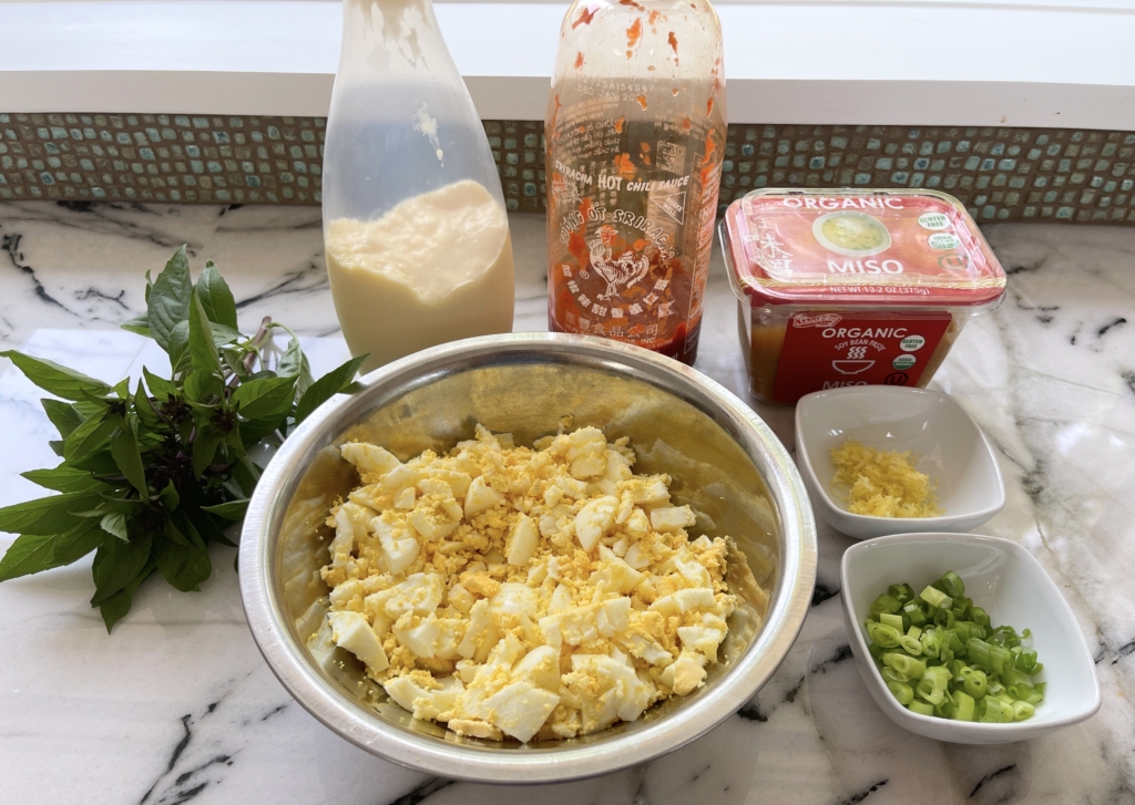 ingredients - chopped hard boiled eggs, gluten free miso paste, kewpie mayonnaise, sriracha, scallions, lemon zest, and thai basil.