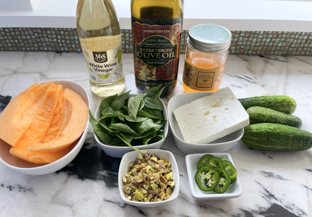 ingredients - cantaloupe, cucumbers, feta, pistachios, fresh basil leaves, jalepeño slices, white wine vinegar, extra virgin olive oil, and honey