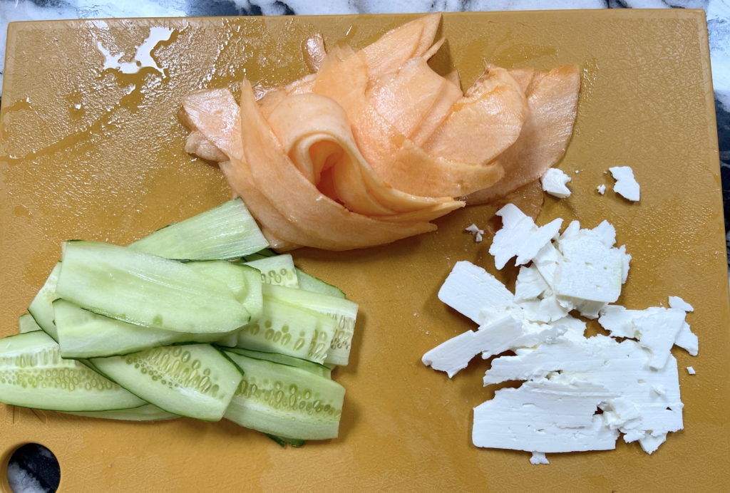 Use a mandoline to thinly slice the melon and cucumbers lengthwise. Then use a slightly wider setting to slice the feta.