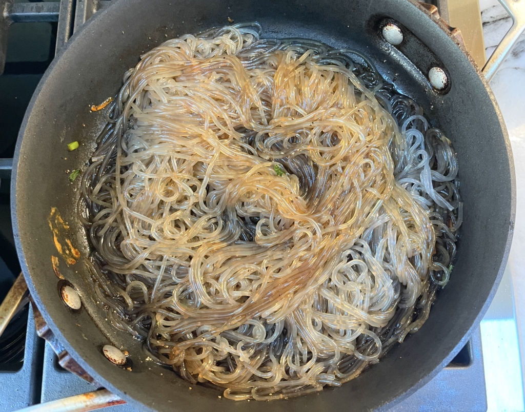 Once the sugar dissolves, add the cooked sweet potato vermicelli noodles back to the pan and using tongs combine the sauce thoroughly with the noodles. 