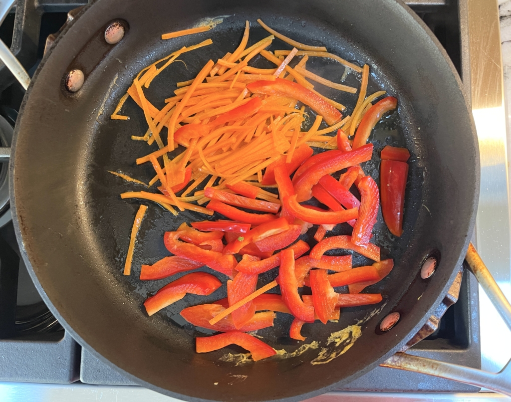 In the same pan, heat another 1 tablespoon of neutral oil over medium to medium-high heat. Cook carrots and red pepper for 3-4 minutes until both have softened. Remove from pan and place into a bowl. 