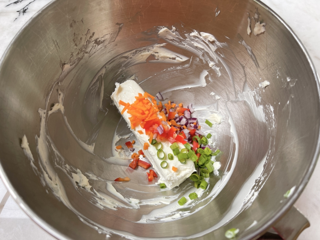 Place cream cheese and vegetables into a bowl.