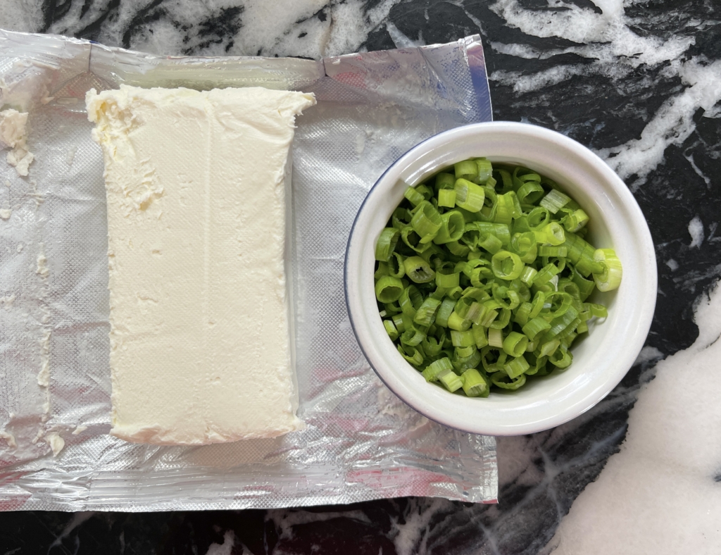 Allow one block of cream cheese to come to room temperature and slice scallions into rounds.