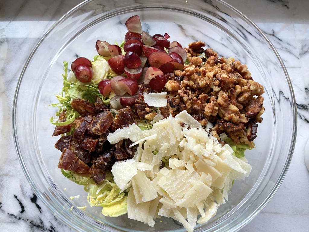 Add the grapes, dates, parmesan cheese and candied walnuts to the bowl with the Brussels sprouts. 