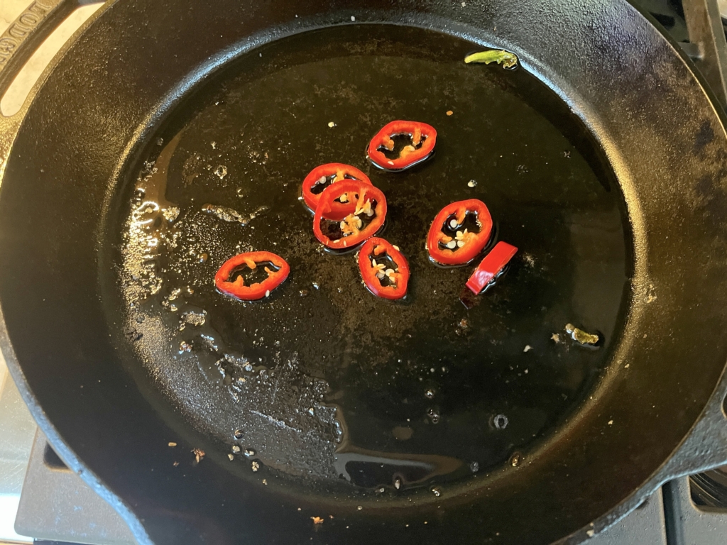 Add remaining 3 tablespoons of oil and heat over medium-high. Add chiles or hot pepper flakes until fragrant, less than 1 minute.